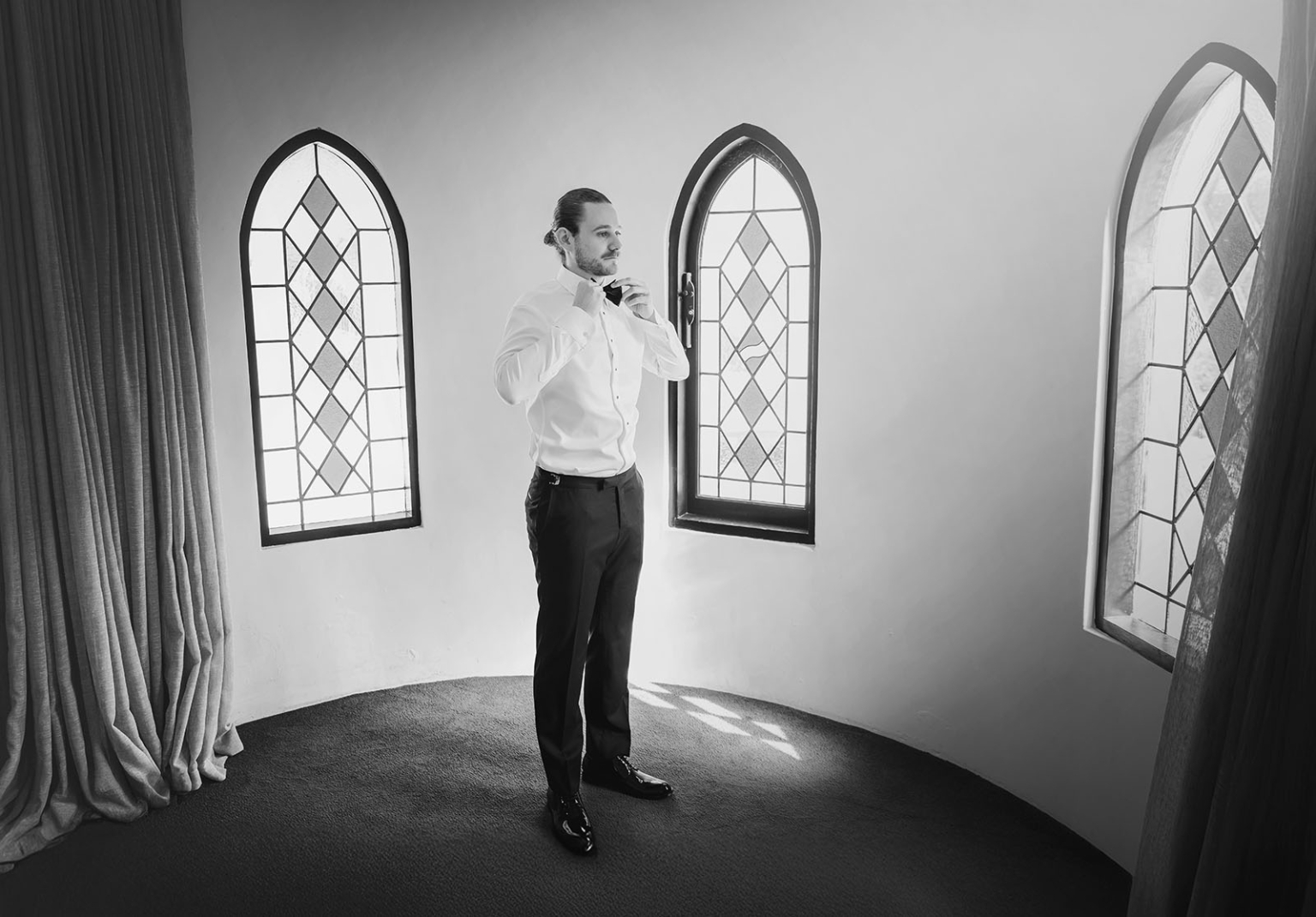 the manor wedding - crystal & mackenzie 4 Groom adjusting bow tie in elegant arched window wedding suite.