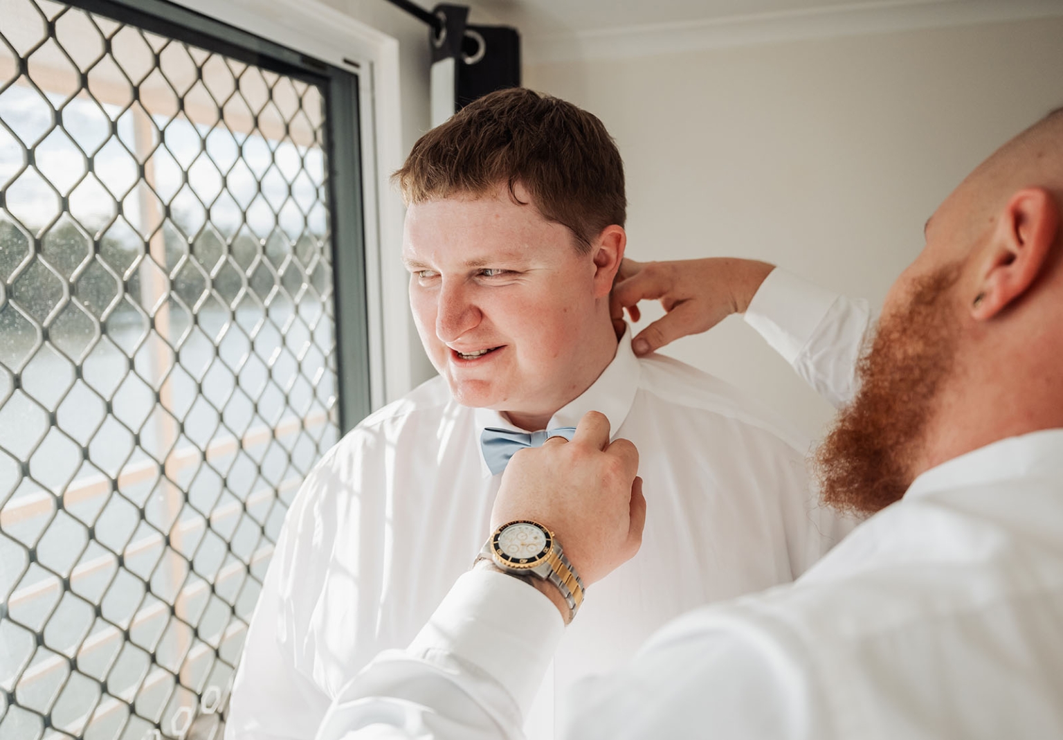 loxton's st peter's church wedding - madeline & brayden 5 Groomsman adjusting groom’s blue bow tie before wedding ceremony.