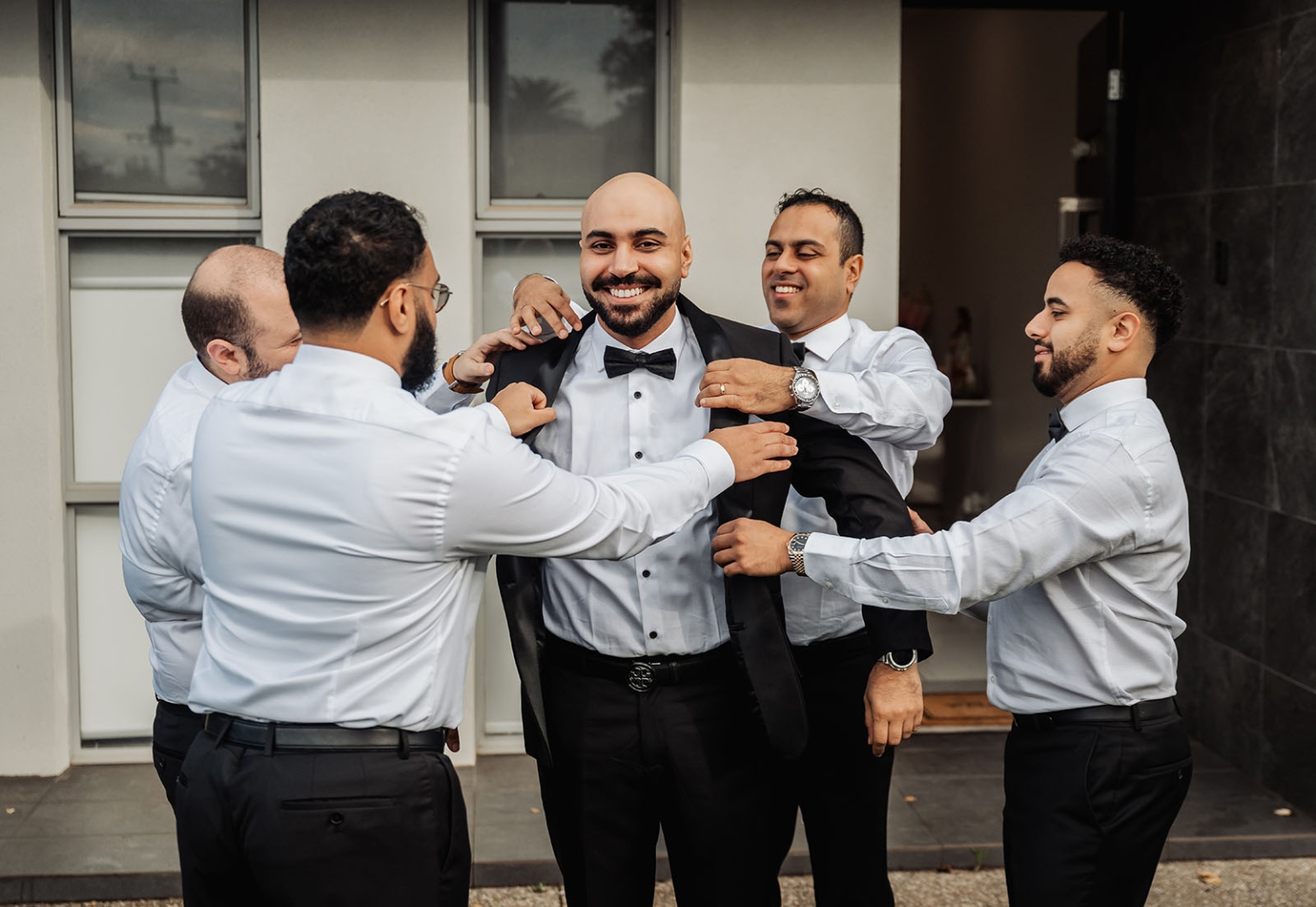 st george & st shenouda coptic church wedding - carmina & bill 7 Groom and groomsmen adjusting tuxedo during wedding preparation.