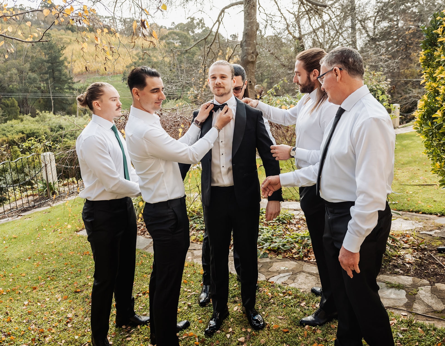 the manor wedding - crystal & mackenzie 7 Groom and groomsmen preparing tuxedo outdoors before wedding ceremony.