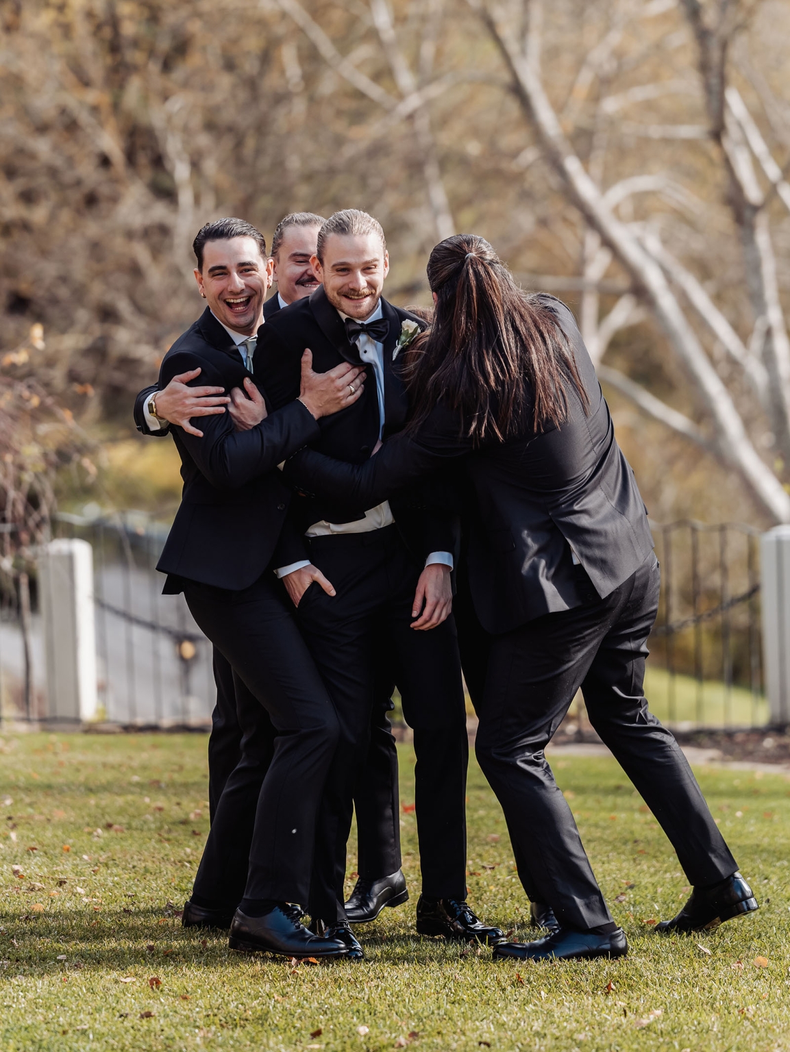 the manor wedding - crystal & mackenzie 11 Laughing groomsmen group hug during outdoor wedding celebration.