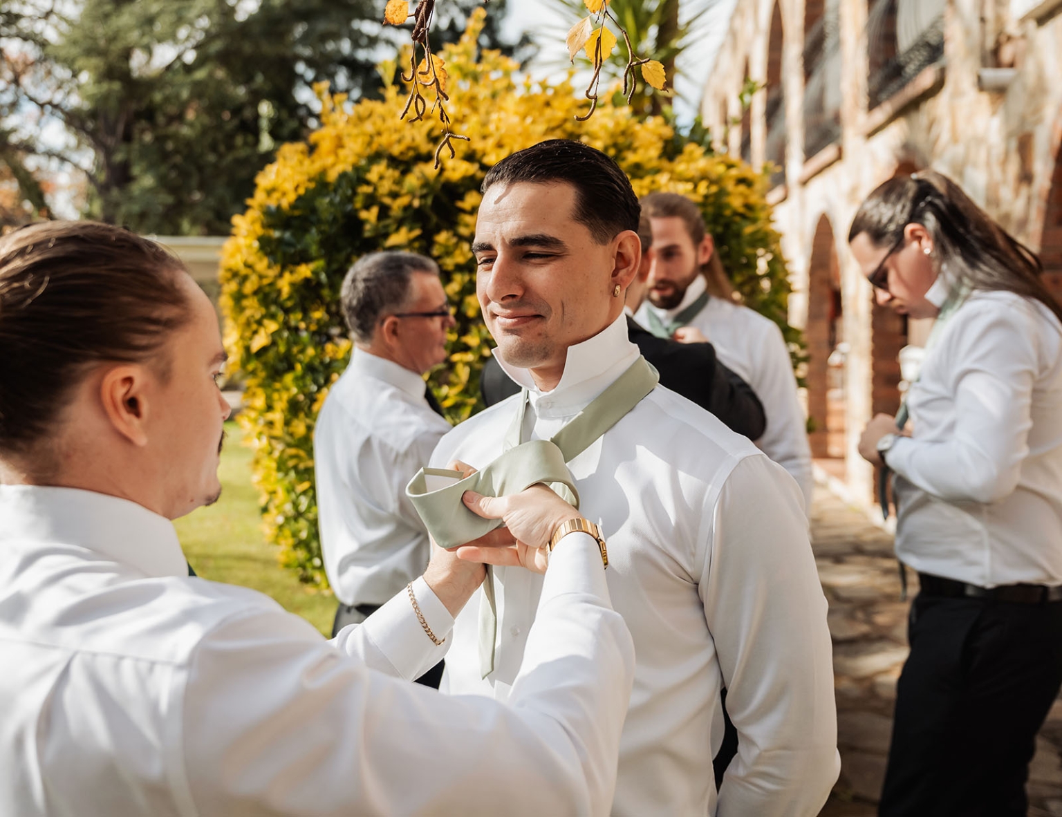 the manor wedding - crystal & mackenzie 8 Groomsmen adjusting sage green tie before outdoor wedding ceremony.