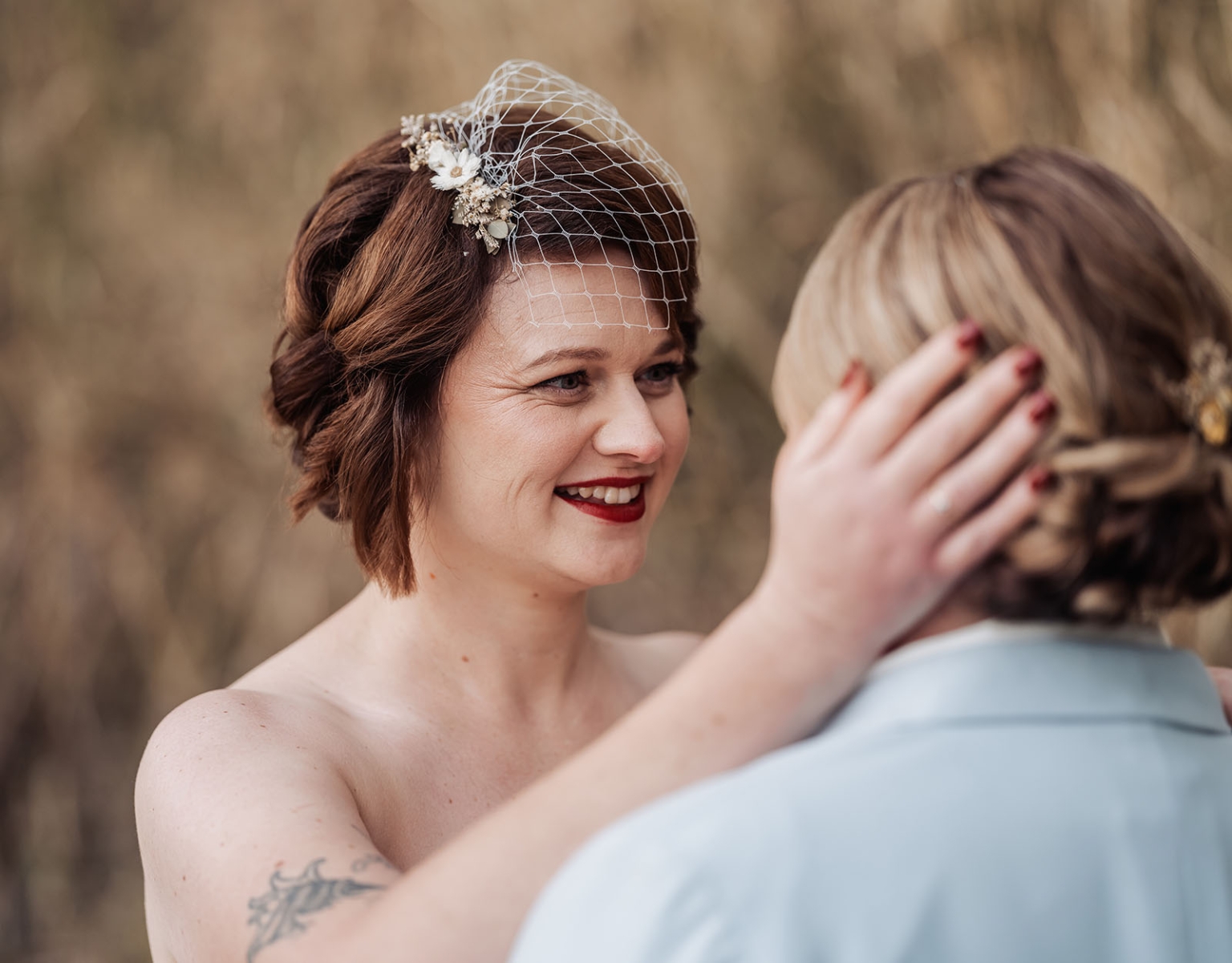 tiny house on the prairie wedding - lauren & bek 48 Intimate wedding portrait of smiling bride with birdcage veil embracing partner outdoors.