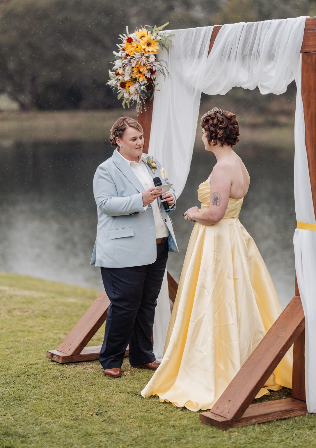 tiny house on the prairie wedding - lauren & bek 28 Lakeside wedding ceremony under floral wooden arch in gentle rain.