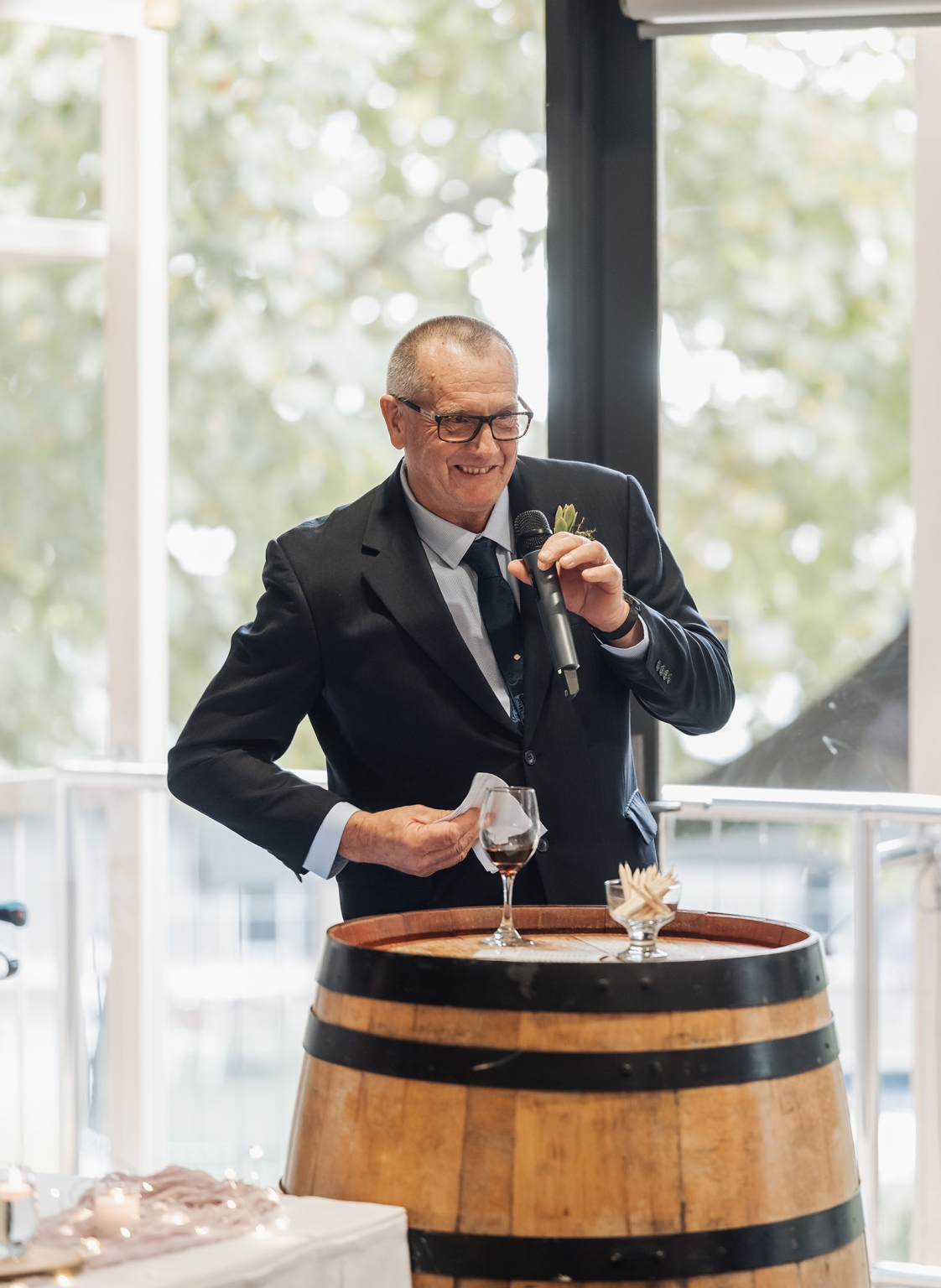 loxton's st peter's church wedding - madeline & brayden 65 Older man giving a wedding toast at a rustic barrel podium.