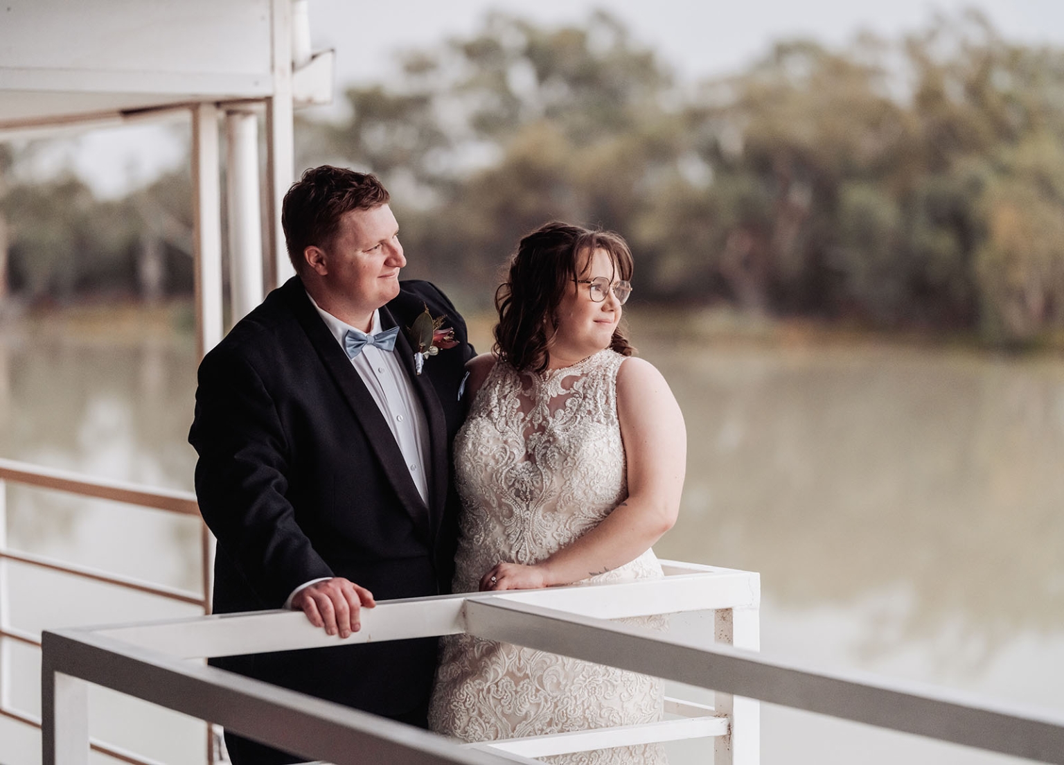 loxton's st peter's church wedding - madeline & brayden 73 Newlywed bride and groom posing on white balcony overlooking lake.