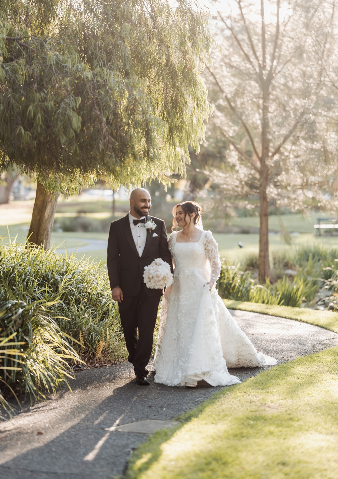 st george & st shenouda coptic church wedding - carmina & bill 60 Newlywed couple walking garden path in romantic outdoor wedding portrait.