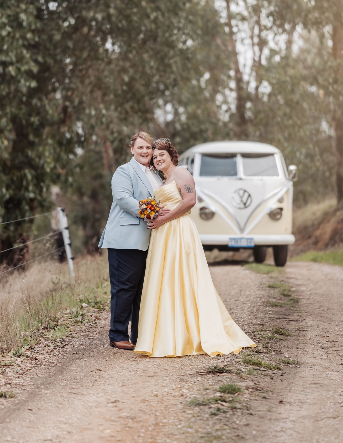 tiny house on the prairie wedding - lauren & bek 16 Newlyweds pose on rustic road with vintage Volkswagen van at outdoor wedding.