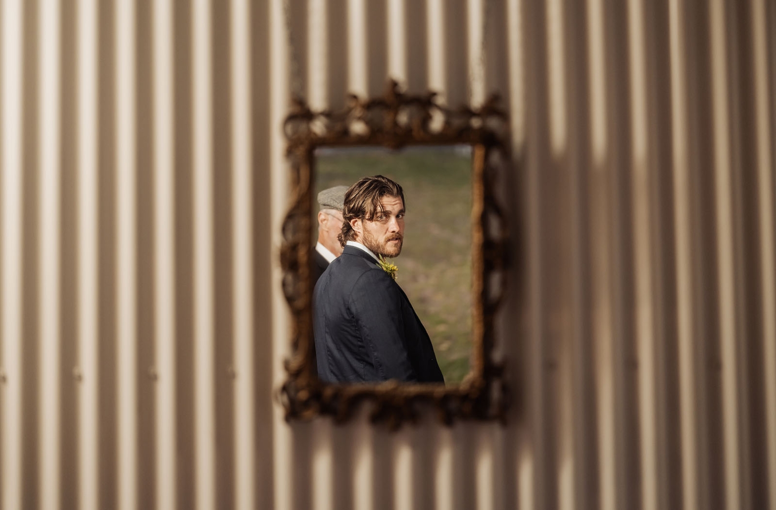 tiny house on the prairie wedding - lauren & bek 60 Groom portrait reflected in ornate mirror on textured wall at elegant wedding.