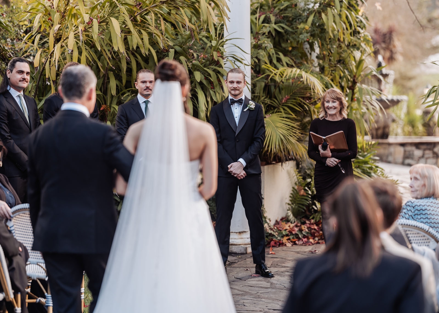 the manor wedding - crystal & mackenzie 48 Bride walks down outdoor garden wedding aisle toward smiling groom.