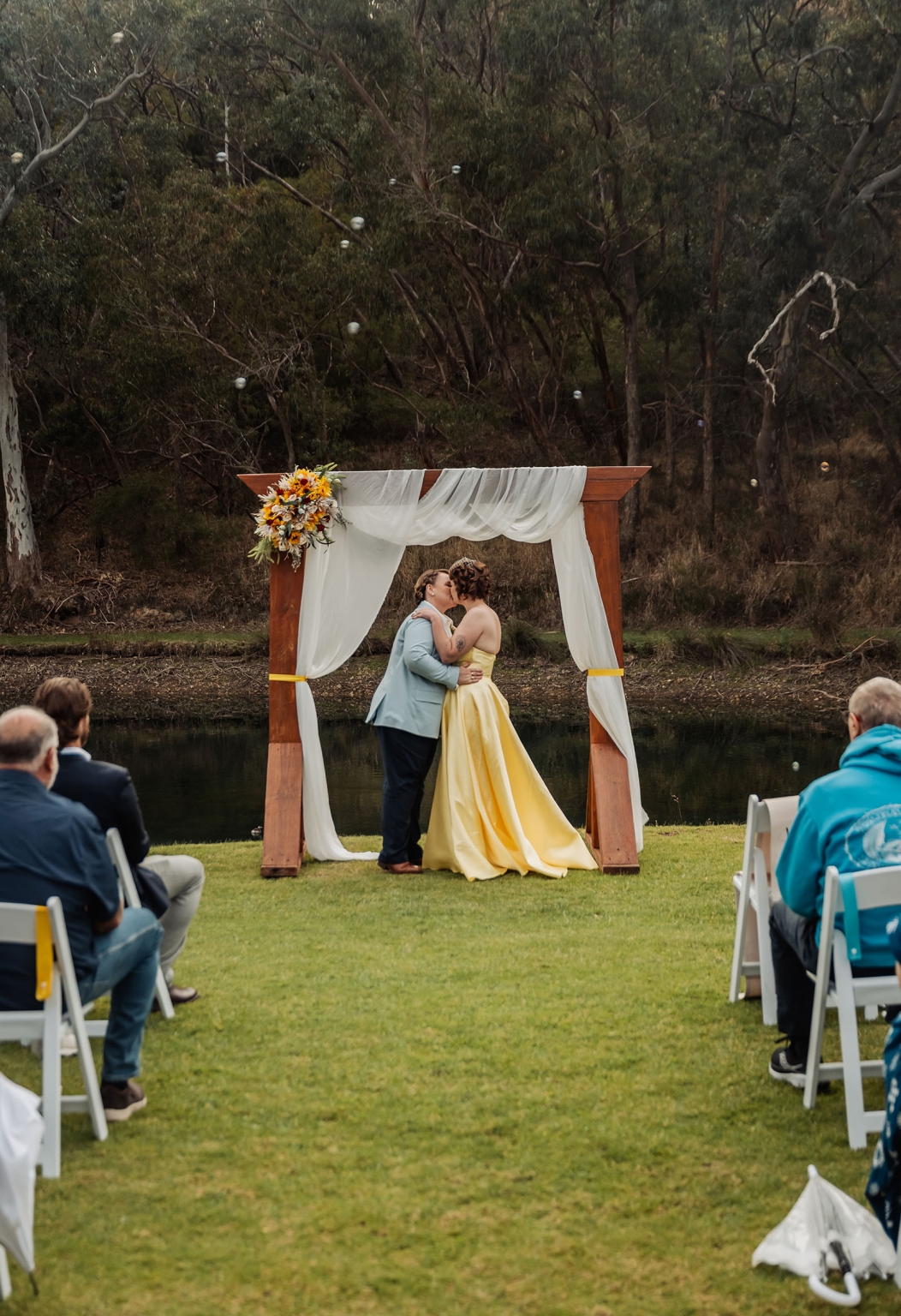tiny house on the prairie wedding - lauren & bek 34 Lakeside outdoor wedding ceremony kiss under wooden floral arch.