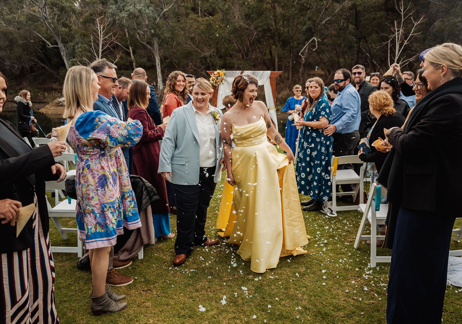 tiny house on the prairie wedding - lauren & bek 35 Newlyweds celebrate outdoor wedding aisle with confetti, guests, and rustic floral arch.