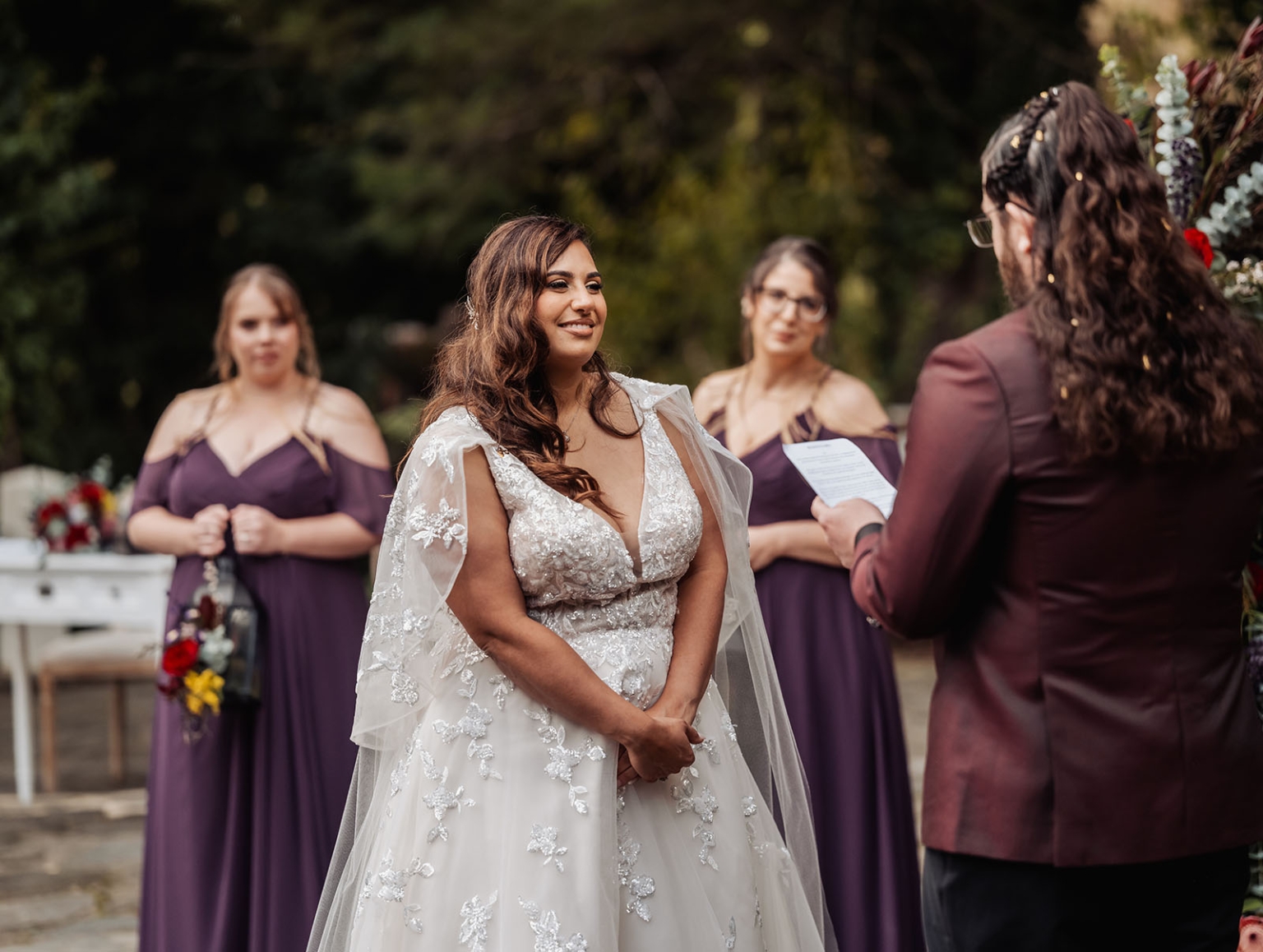 basket range wedding at the manor - leah & wes 49 Bride smiles during outdoor wedding vows with partner in burgundy suit.