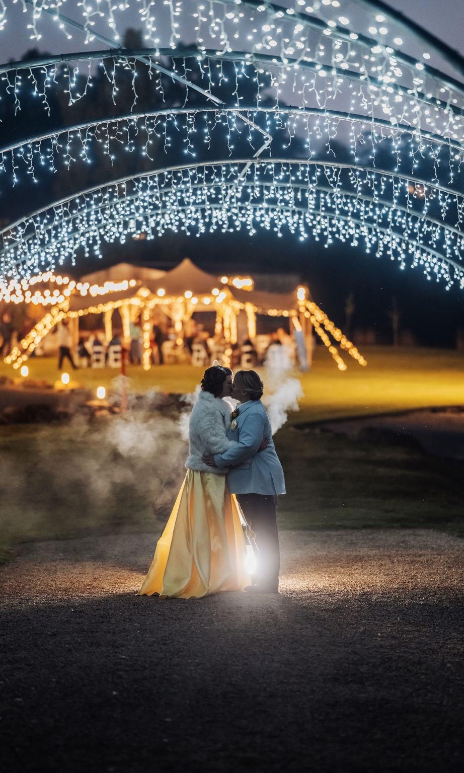 tiny house on the prairie wedding - lauren & bek 51 Romantic wedding kiss under sparkling string lights at nighttime reception.