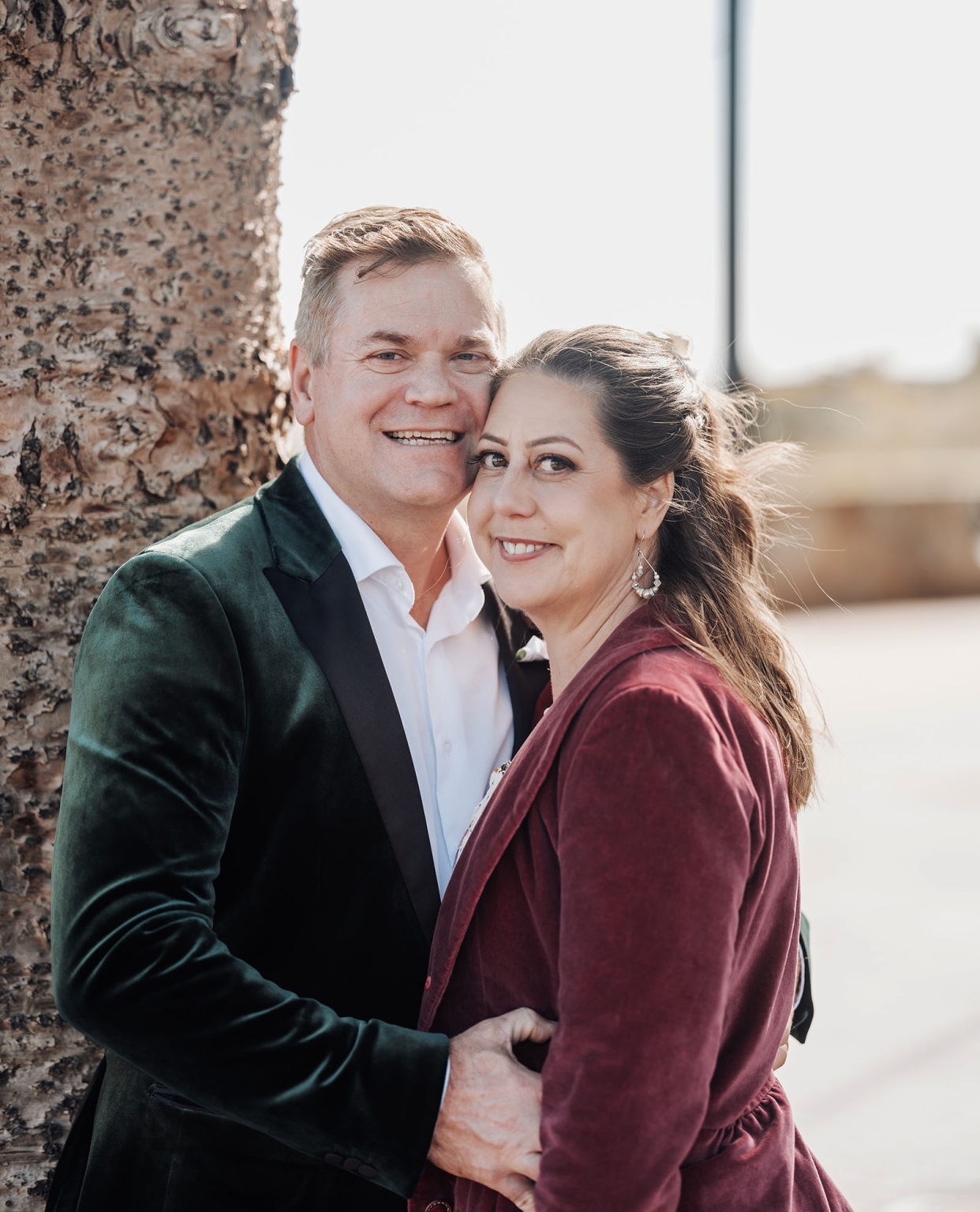 sa marriage office wedding – melissa & kyran 228 Smiling couple in formal velvet attire posing by tree outdoors.