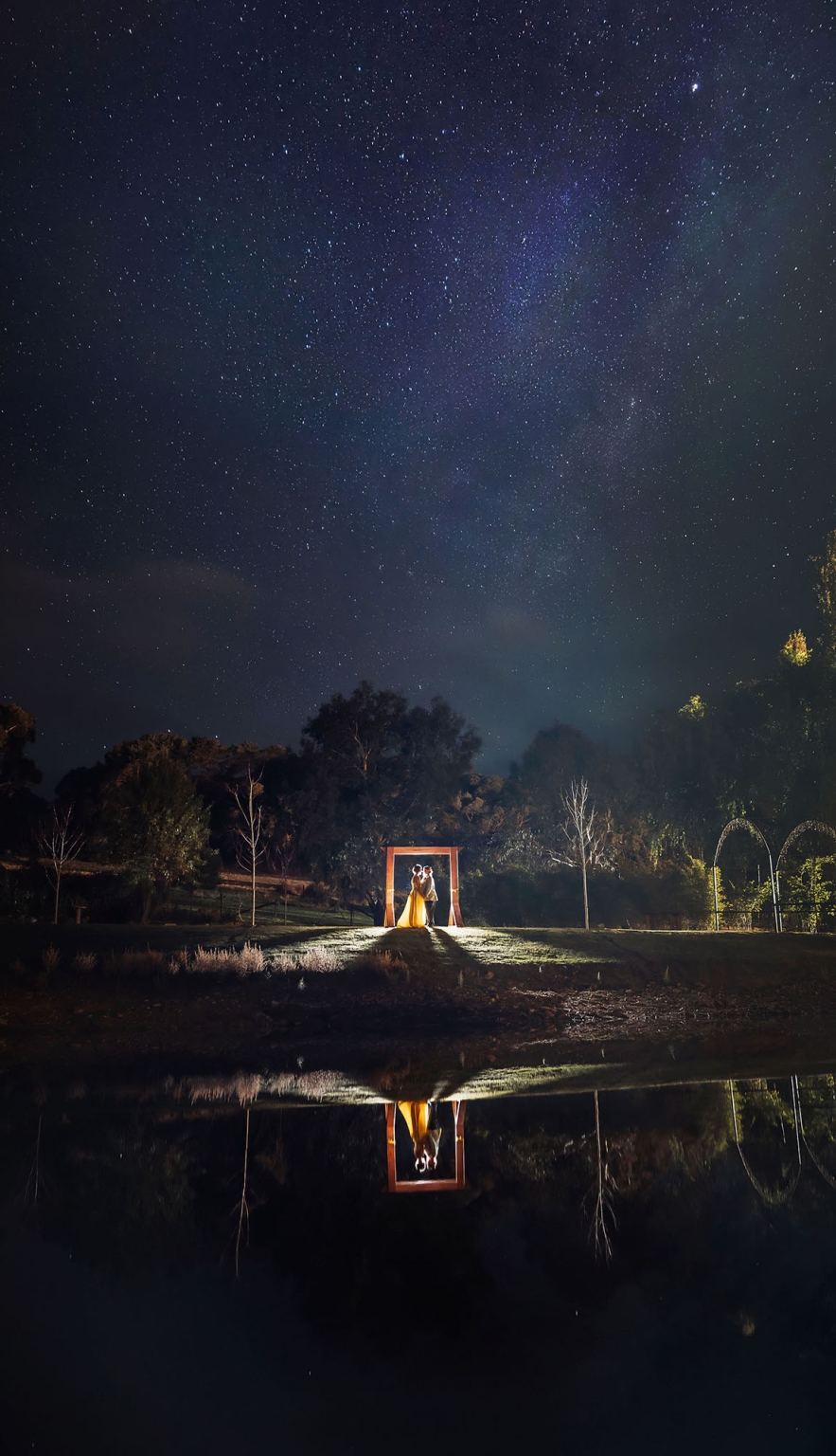 tiny house on the prairie wedding - lauren & bek 53 Starry night wedding couple under wooden arch with romantic water reflection.