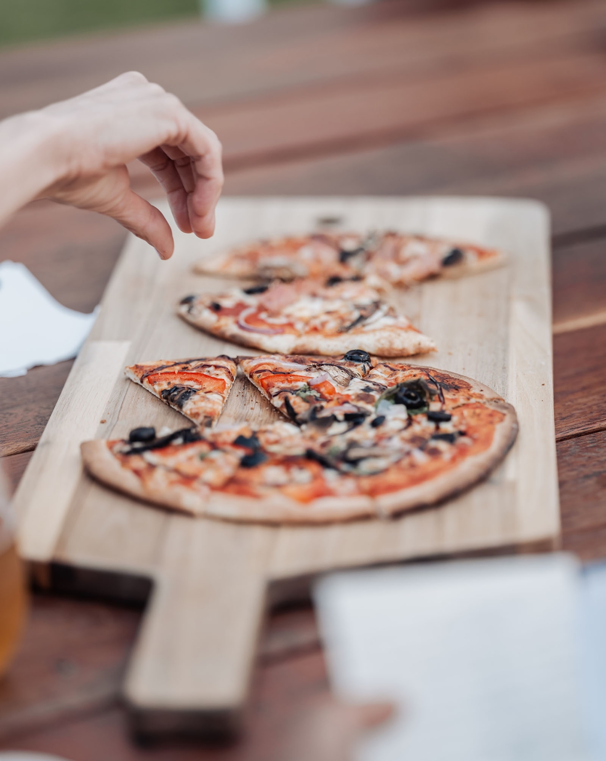 tiny house on the prairie wedding - lauren & bek 56 Hand sprinkling herbs on thin-crust vegetable pizza on wooden board.