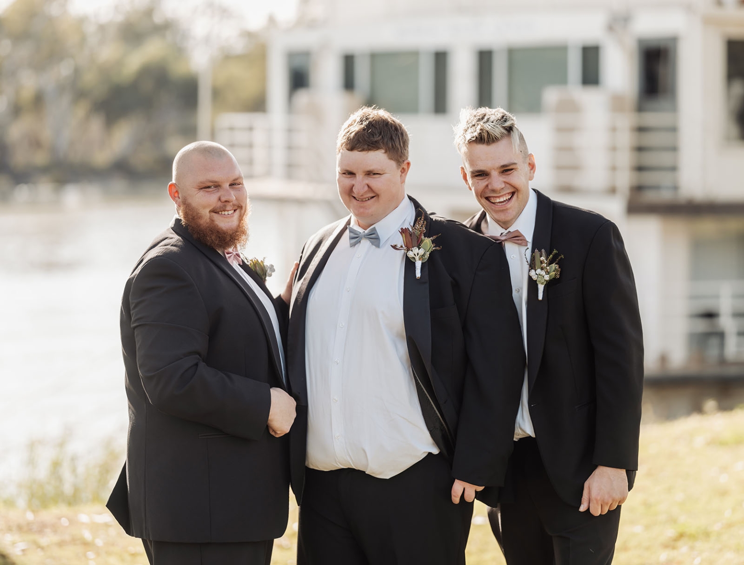 loxton's st peter's church wedding - madeline & brayden 12 Three groomsmen in black suits with boutonnieres posing at an outdoor wedding.
