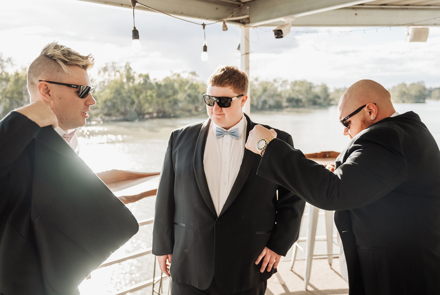 loxton's st peter's church wedding - madeline & brayden 8 Groomsmen in black suits on a sunny waterfront wedding deck.