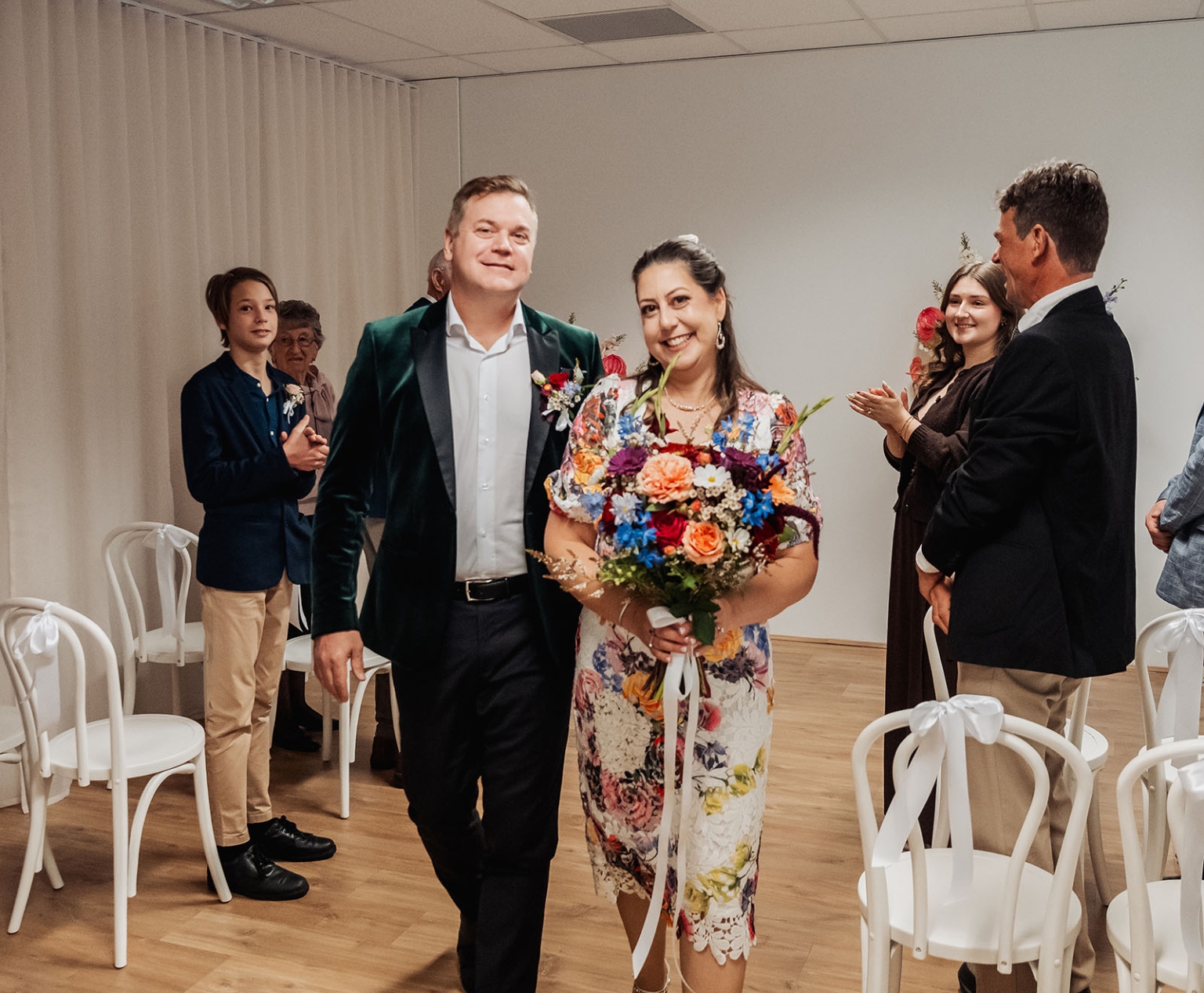 sa marriage office wedding – melissa & kyran 208 Joyful wedding couple walking down aisle with colorful bouquet as guests applaud.