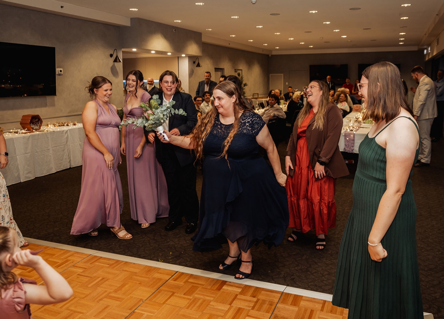 loxton's st peter's church wedding - madeline & brayden 71 Wedding bouquet toss at a joyful indoor reception with laughing bridesmaids and guests.