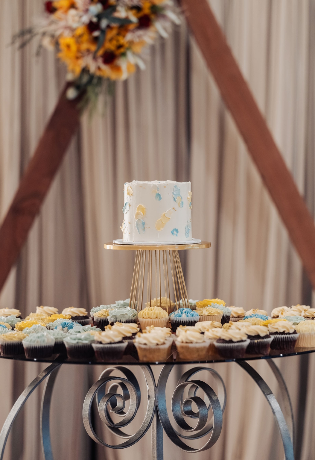 tiny house on the prairie wedding - lauren & bek 55 Wedding cake and cupcake dessert display with pastel buttercream on gold stand.