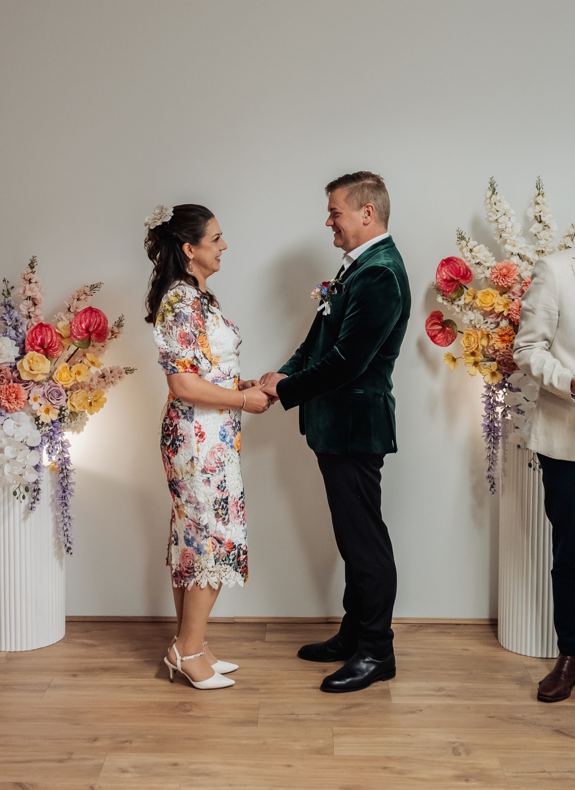 sa marriage office wedding – melissa & kyran 200 Wedding couple holding hands during floral ceremony with colorful arrangements.