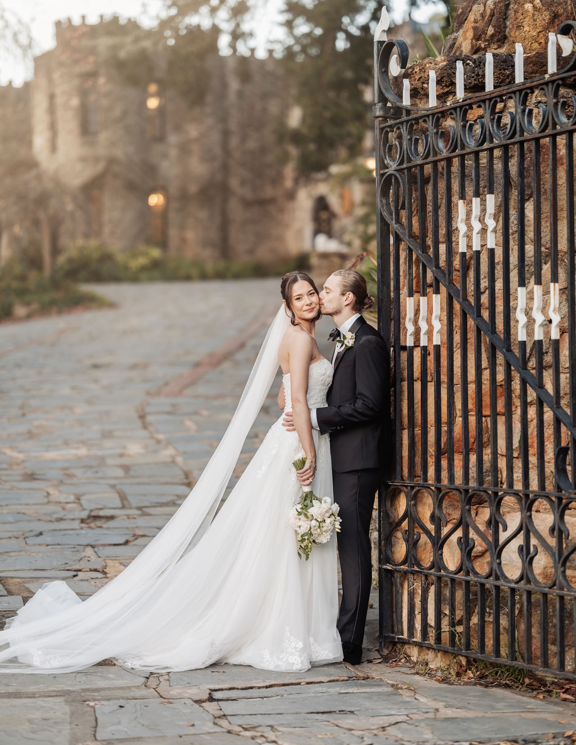 the manor wedding - crystal & mackenzie 77 Bride and groom wedding portrait by ornate iron gate with flowing veil.
