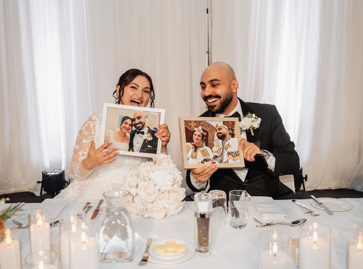 st george & st shenouda coptic church wedding - carmina & bill 84 Joyful newlywed couple at wedding reception holding framed portraits and laughing.