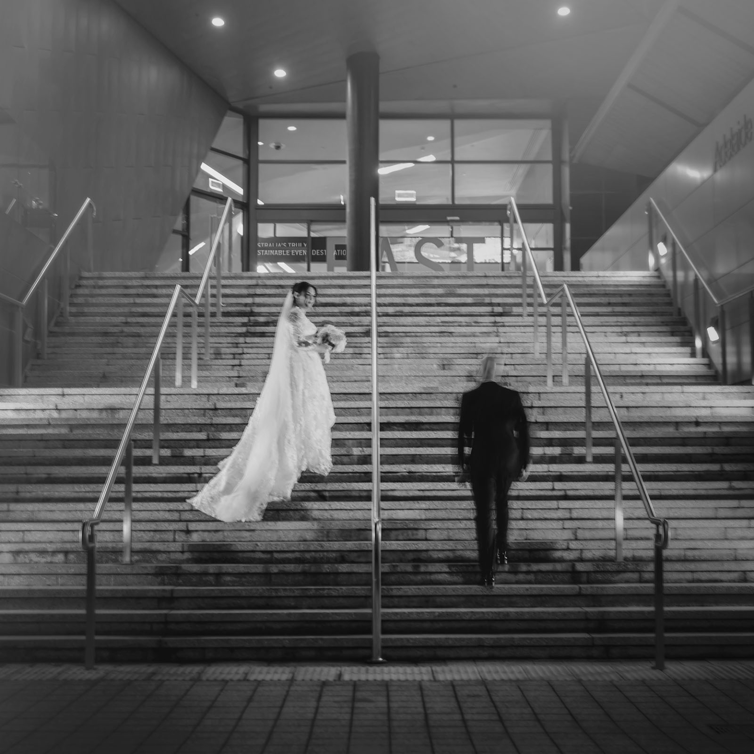 st george & st shenouda coptic church wedding - carmina & bill 76 Wedding bride and groom on stone steps outside modern building at night.