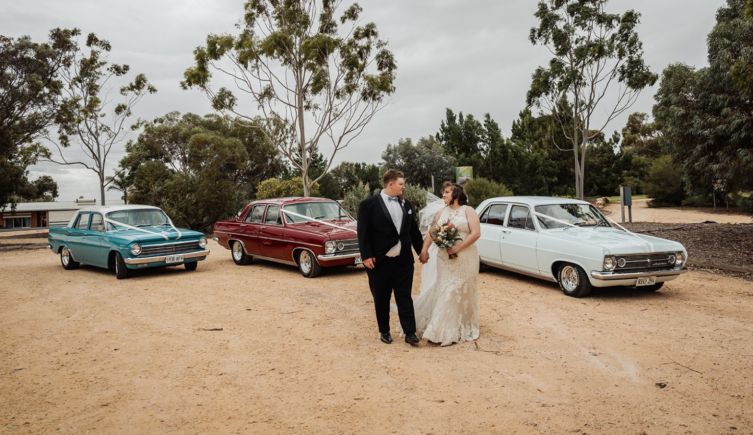 loxton's st peter's church wedding - madeline & brayden 45 Wedding couple posing with vintage cars on rustic countryside road.