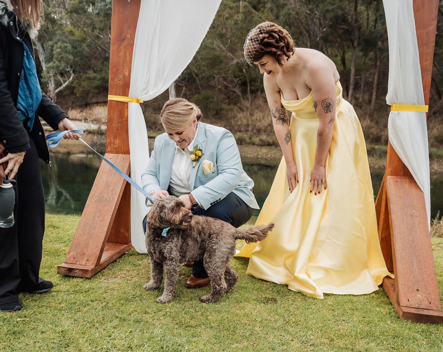 tiny house on the prairie wedding - lauren & bek 32 Rustic outdoor wedding ceremony with bride, partner, and dog by lakeside arch.
