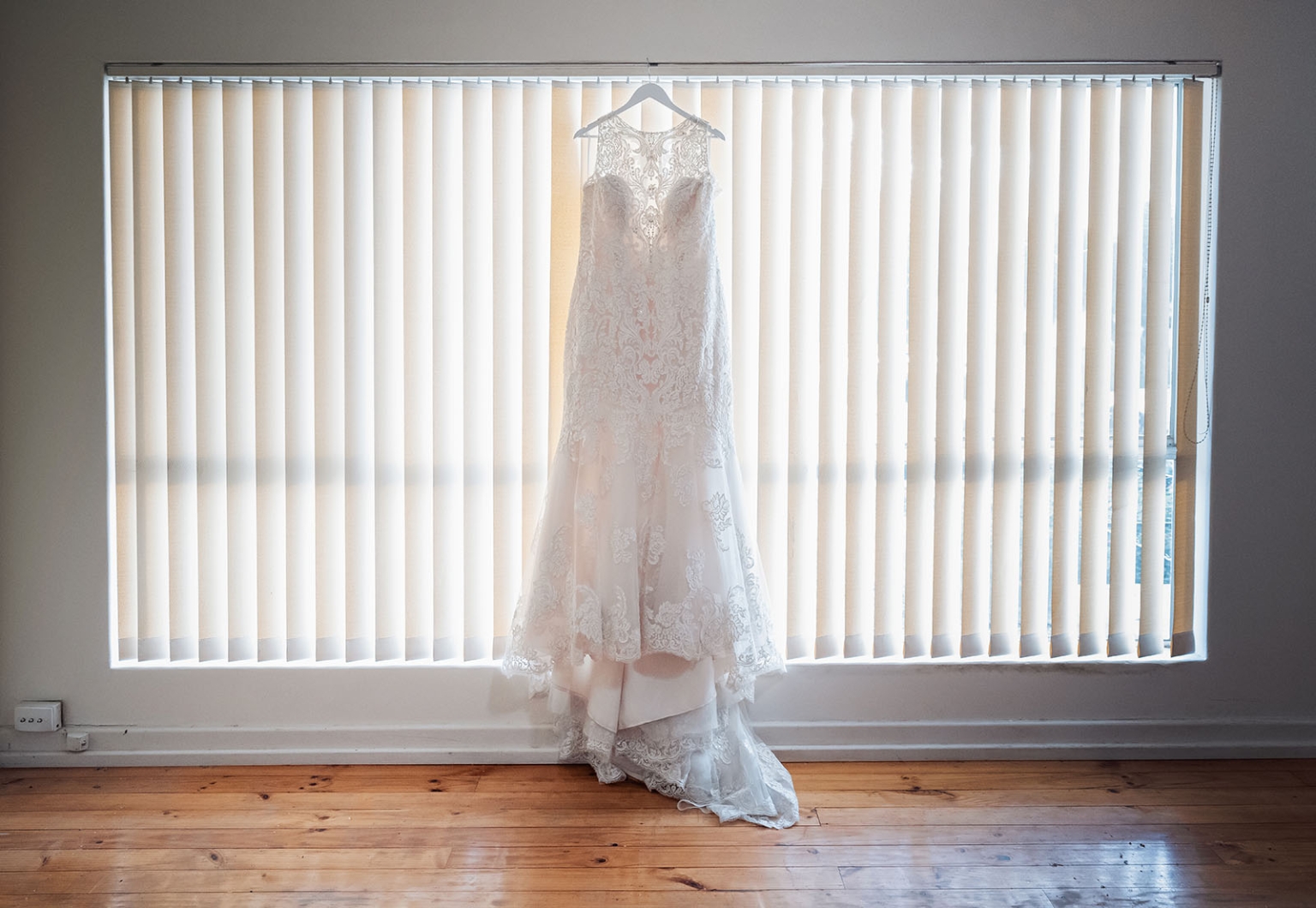 loxton's st peter's church wedding - madeline & brayden 18 Ivory lace wedding dress hanging in sunlit window before ceremony.