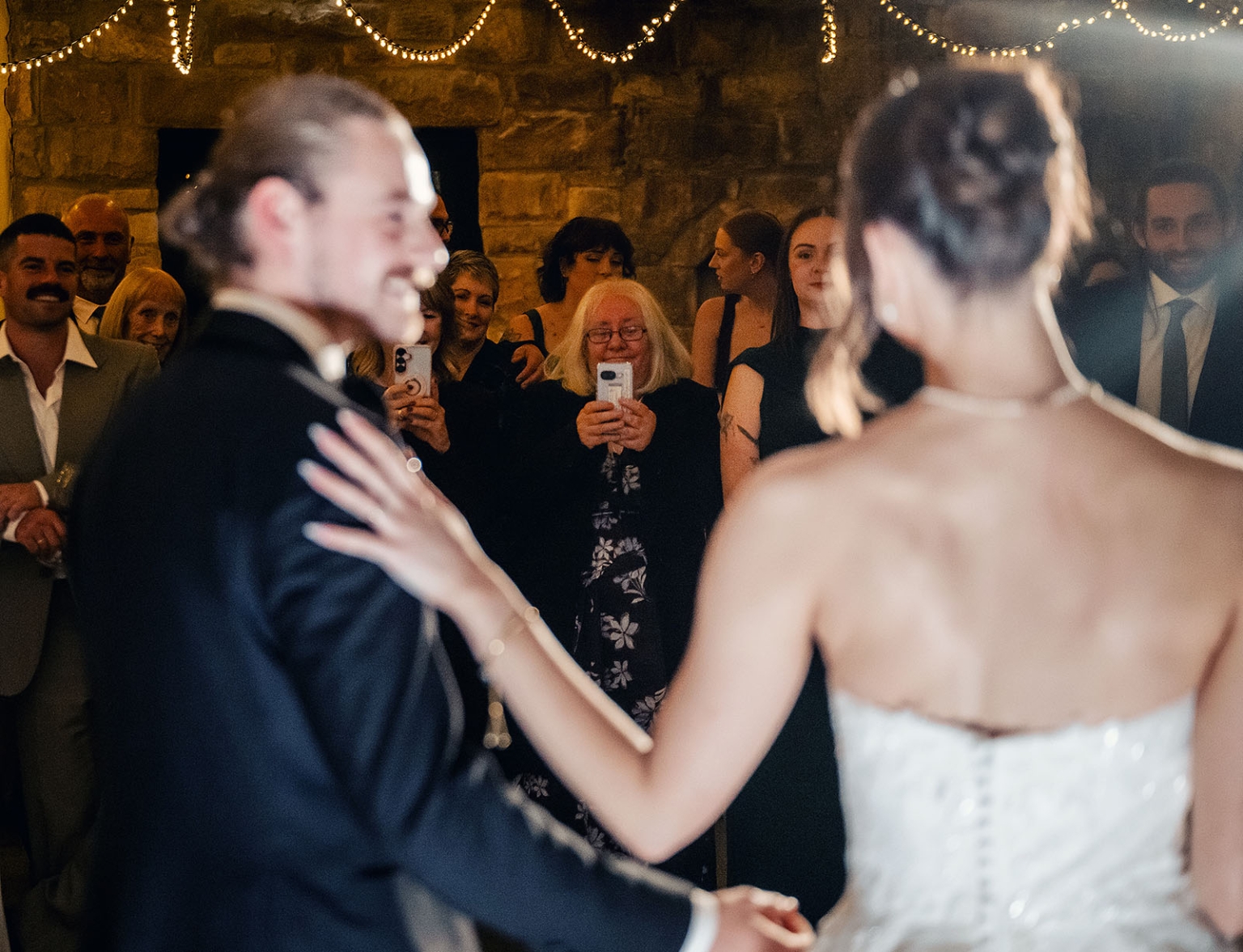 the manor wedding - crystal & mackenzie 93 Bride and groom first dance at rustic wedding reception with smiling guests.