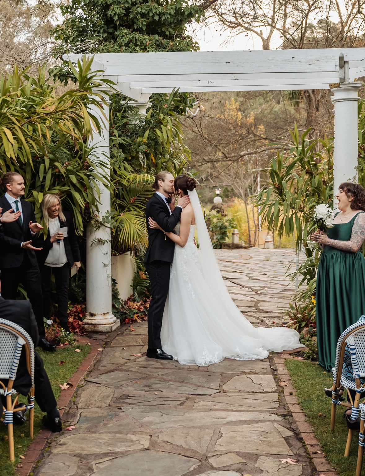 the manor wedding - crystal & mackenzie 57 Bride and groom first kiss under garden pergola at outdoor wedding ceremony.
