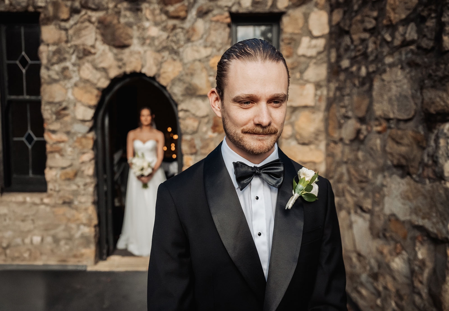 the manor wedding - crystal & mackenzie 37 Groom in black tuxedo with bride at rustic stone wedding venue.