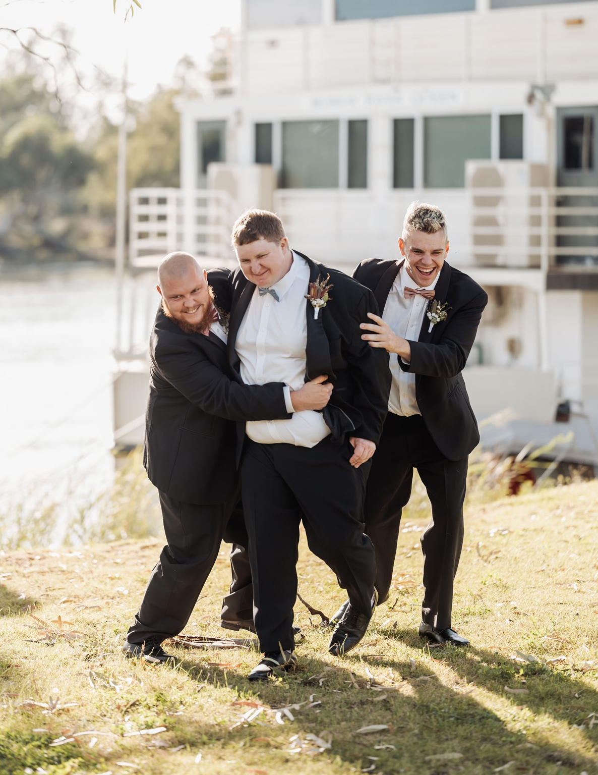 loxton's st peter's church wedding - madeline & brayden 11 Laughing wedding groomsmen in black suits during outdoor portrait.