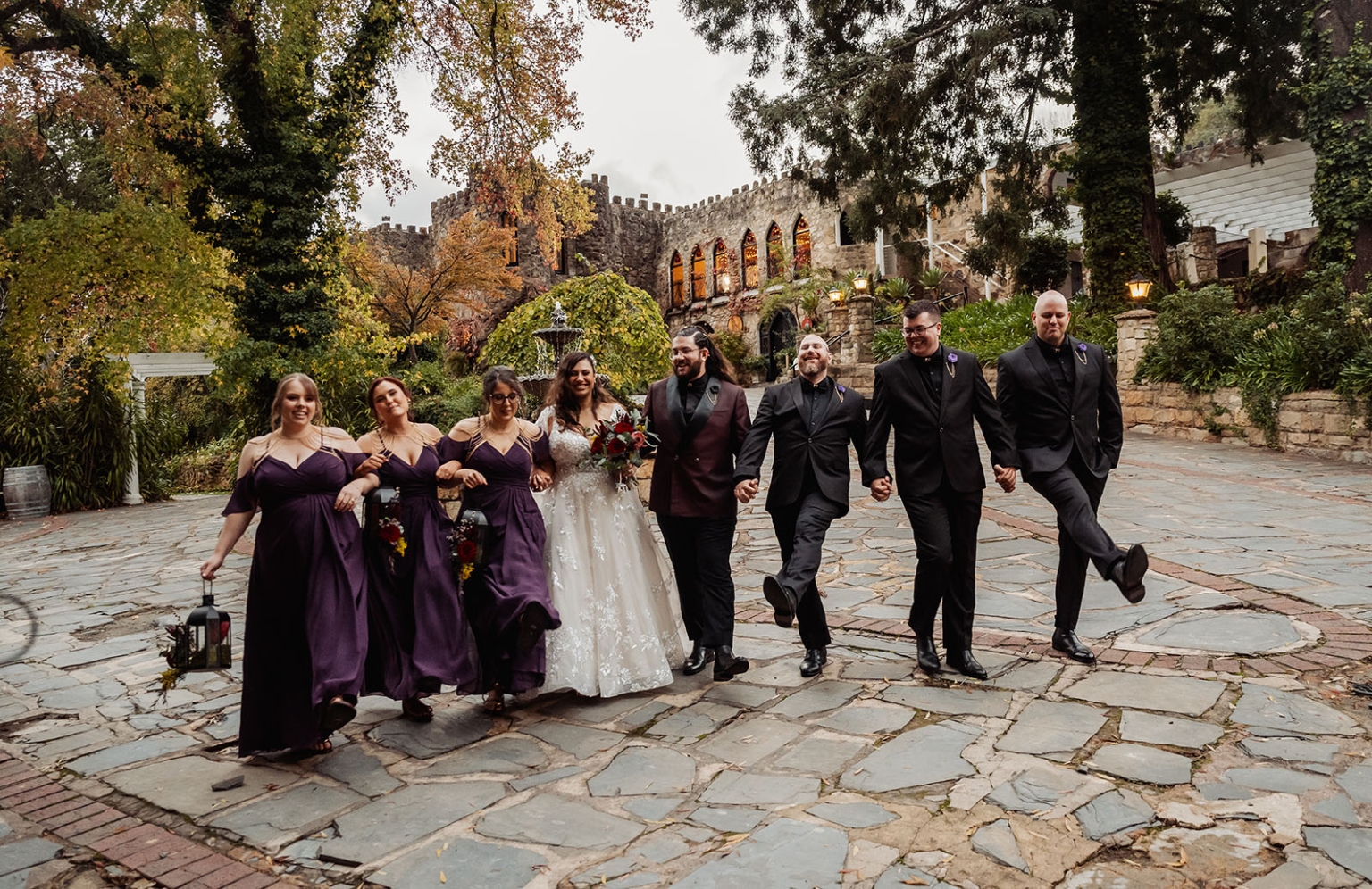 basket range wedding at the manor - leah & wes 61 Wedding party walking through castle courtyard with autumn foliage and historic stone venue.