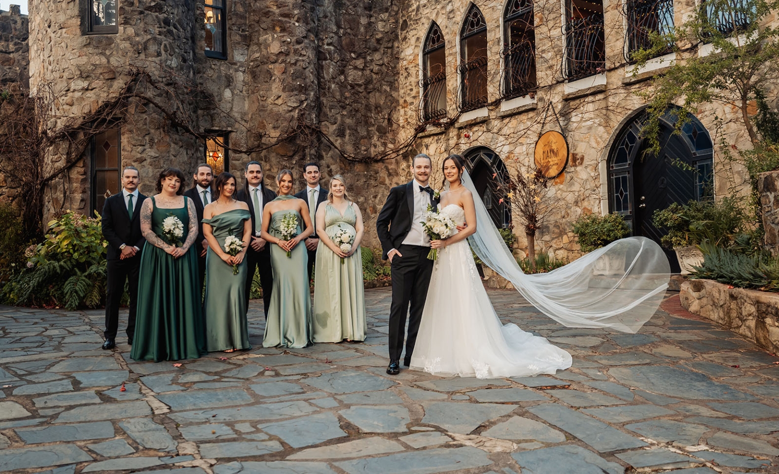 the manor wedding - crystal & mackenzie 73 Wedding party portrait in stone courtyard with bride, groom, bridesmaids, and groomsmen.