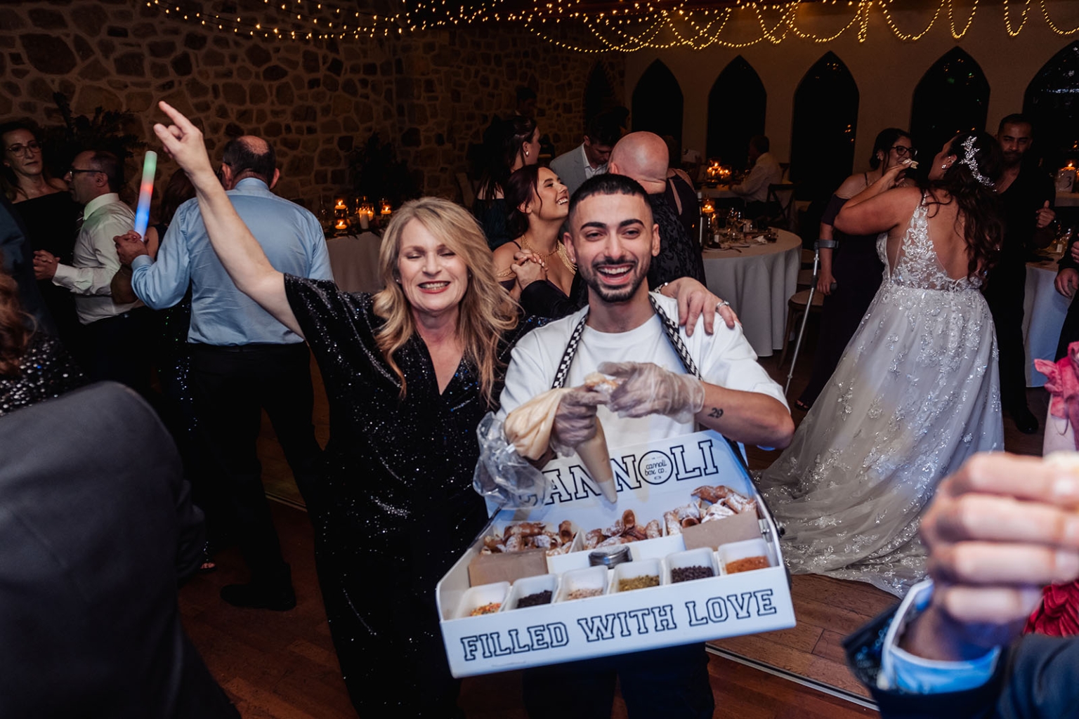 basket range wedding at the manor - leah & wes 76 Cannoli server delights guests at lively rustic wedding reception with bride dancing.