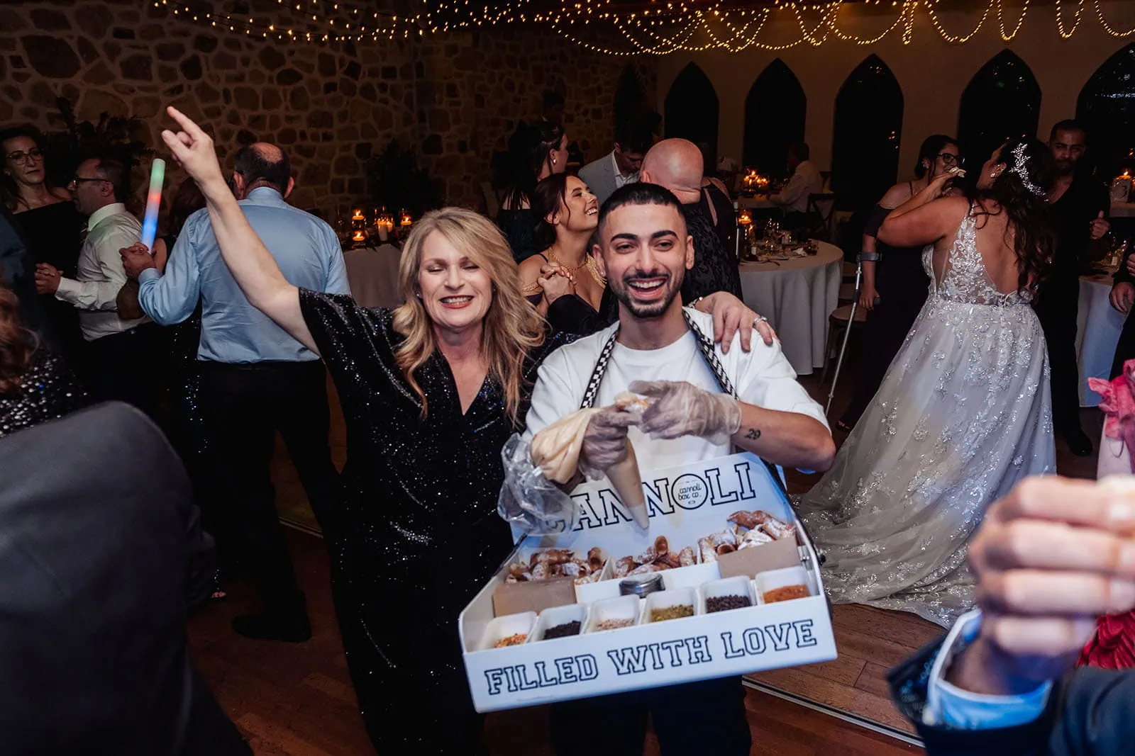 cannoli server energizes rustic wedding reception Cannoli server delights guests at lively rustic wedding reception with bride dancing.
