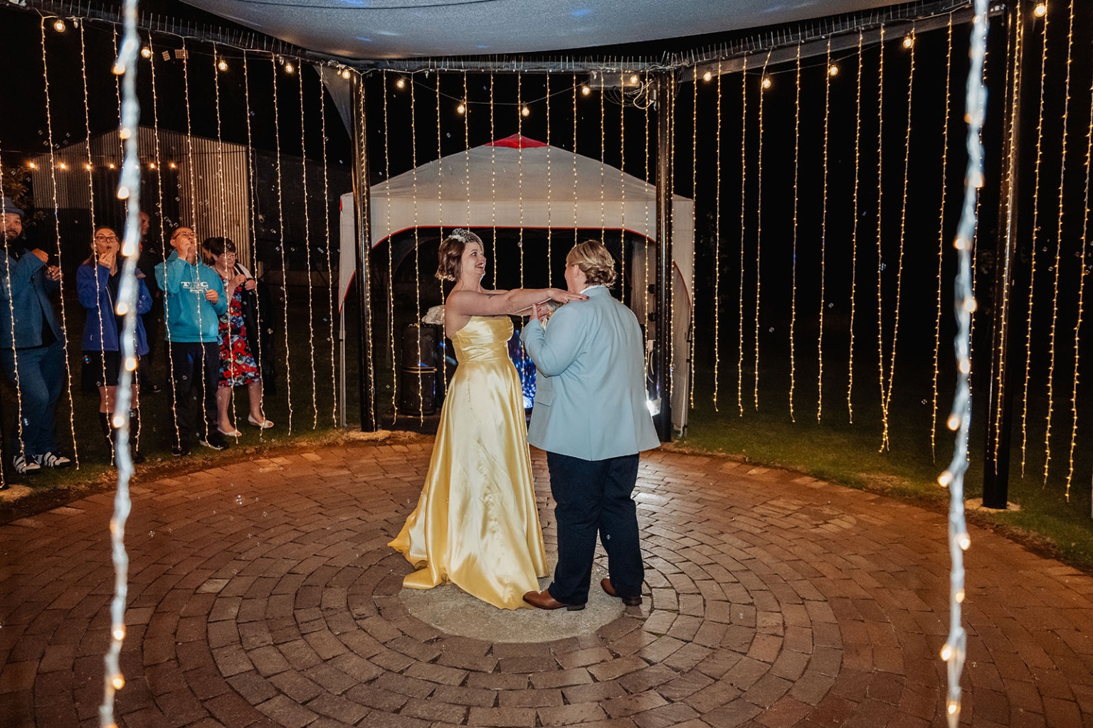 tiny house on the prairie wedding - lauren & bek 64 Wedding reception dance under romantic string lights on an outdoor brick patio.