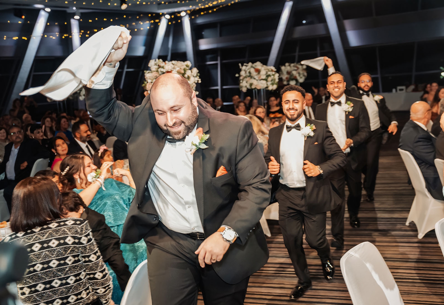 st george & st shenouda coptic church wedding - carmina & bill 81 Groomsmen in tuxedos wave napkins during joyful wedding reception procession.