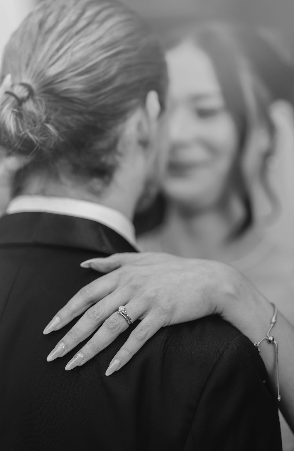 the manor wedding - crystal & mackenzie 83 Sparkling wedding ring on bride’s hand during romantic embrace.