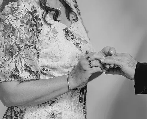 Bride and groom exchanging wedding rings during intimate black-and-white ceremony.