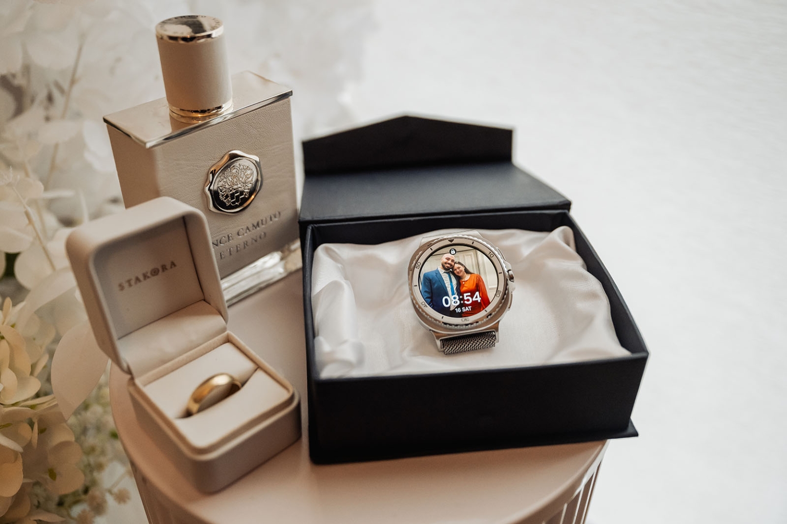 st george & st shenouda coptic church wedding - carmina & bill 2 Wedding ring, perfume, and smartwatch displayed as elegant groom accessories.