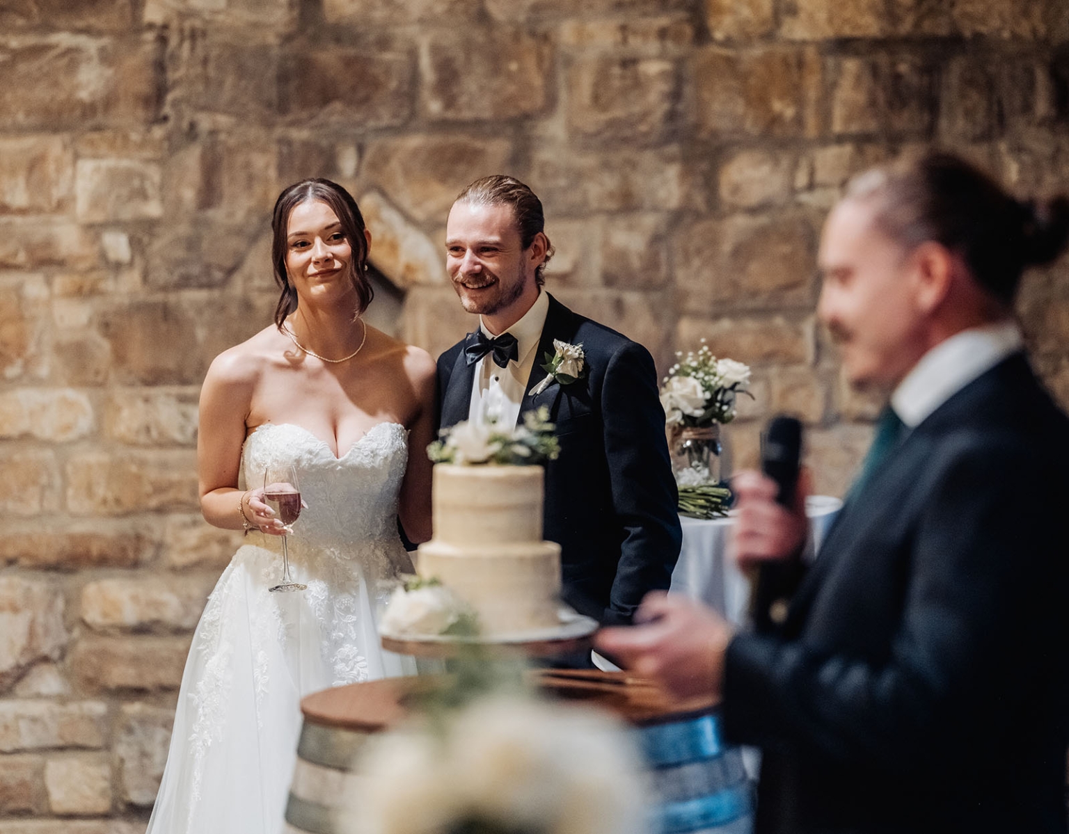 the manor wedding - crystal & mackenzie 88 Bride and groom smile during wedding toast beside elegant cake.