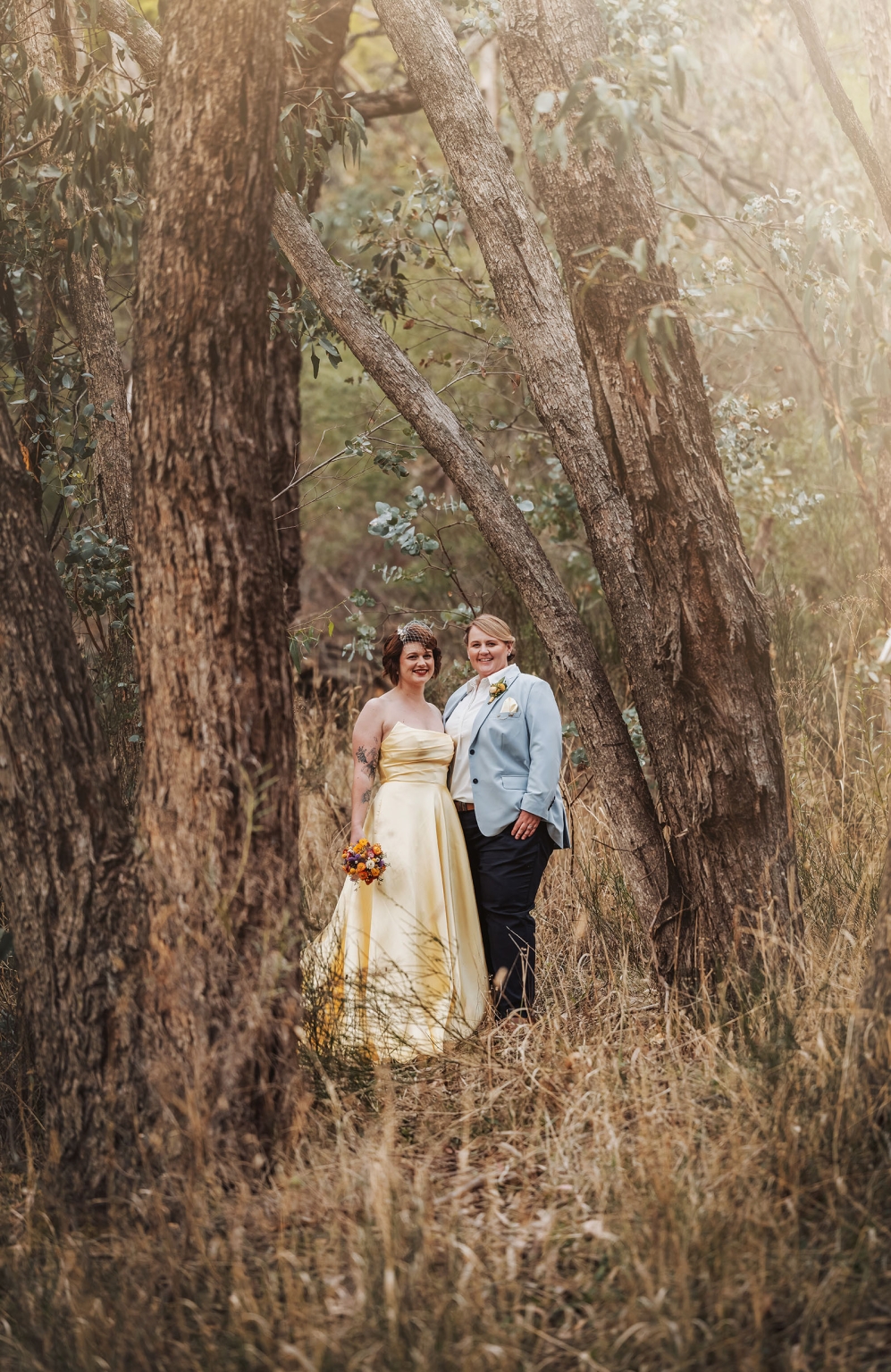 tiny house on the prairie wedding - lauren & bek 38 Woodland wedding couple posing in golden forest with bouquet and blue blazer.