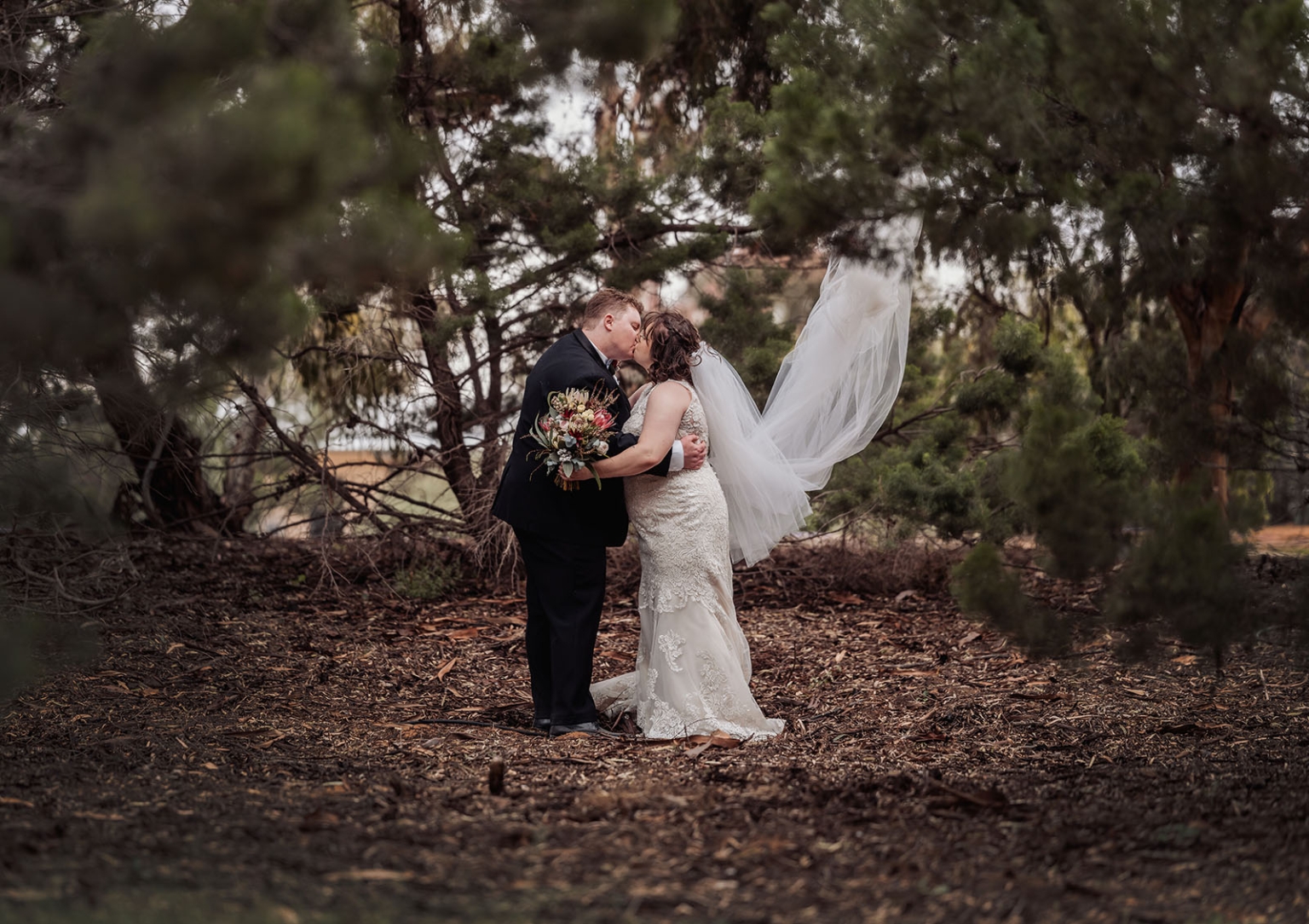 loxton's st peter's church wedding - madeline & brayden 52 Woodland wedding couple kissing, bride in lace gown with flowing veil.