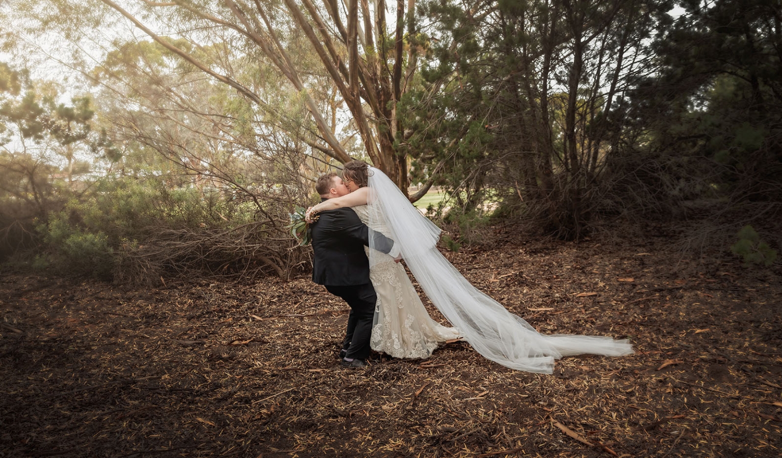 loxton's st peter's church wedding - madeline & brayden 56 Bride and groom kiss in enchanted woodland wedding with flowing veil.